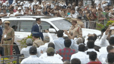 a man in a suit stands in front of a white suv