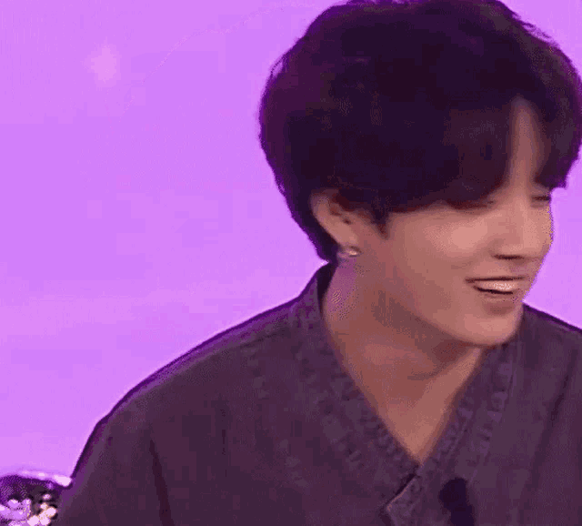 a close up of a person 's face with a purple background and a microphone .