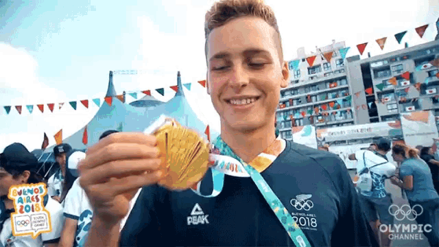 a man wearing a peak shirt is holding up a medal