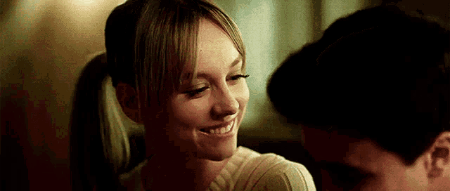 a woman is smiling at a man in a dark room .