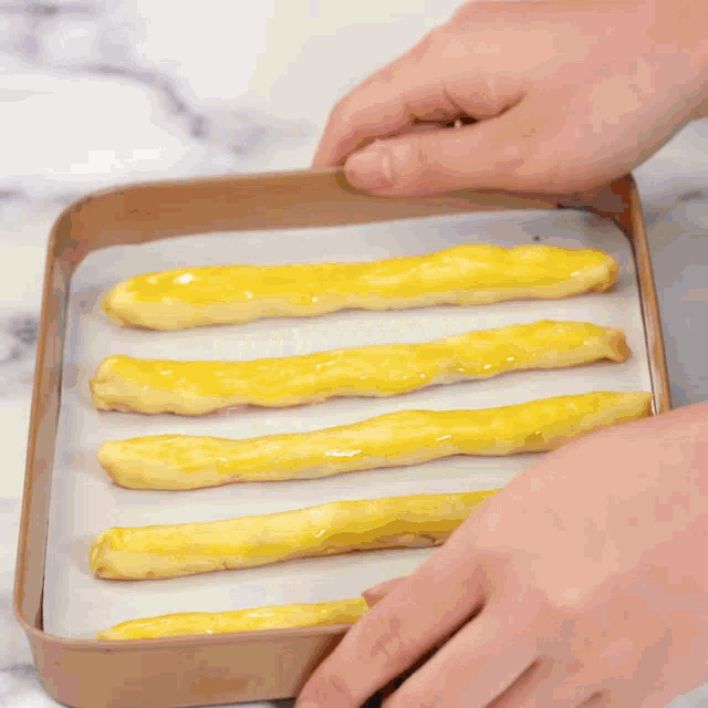 a person is spreading frosting on a piece of food on a wooden cutting board