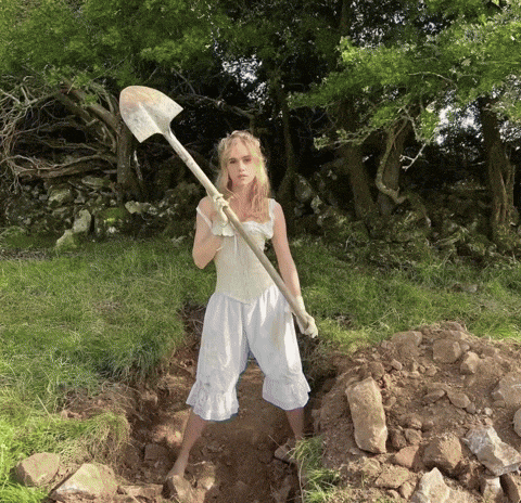 a woman in a white dress is holding a shovel