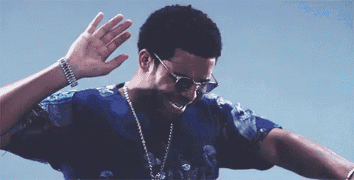 a man wearing sunglasses and a blue shirt is waving his hand