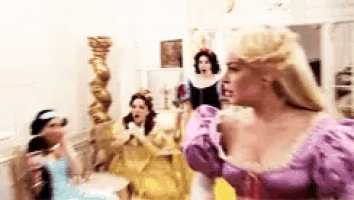 a woman in a purple dress is standing in a room with other women dressed as princesses .