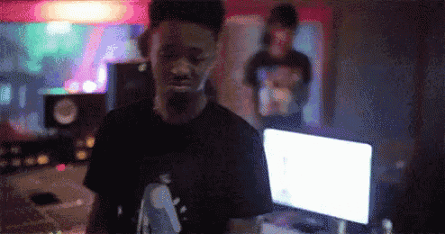 a man in a black shirt is standing in front of a computer in a room .