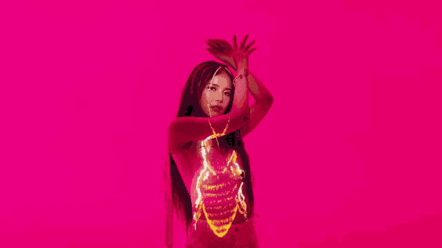 a woman is dancing in front of a pink background