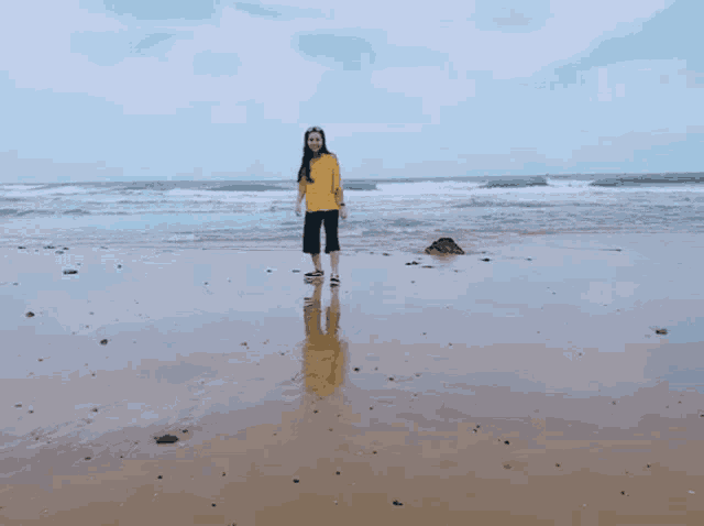 a woman in a yellow sweatshirt is running on a beach