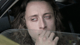 a man with long hair is sitting in a car and looking out the window