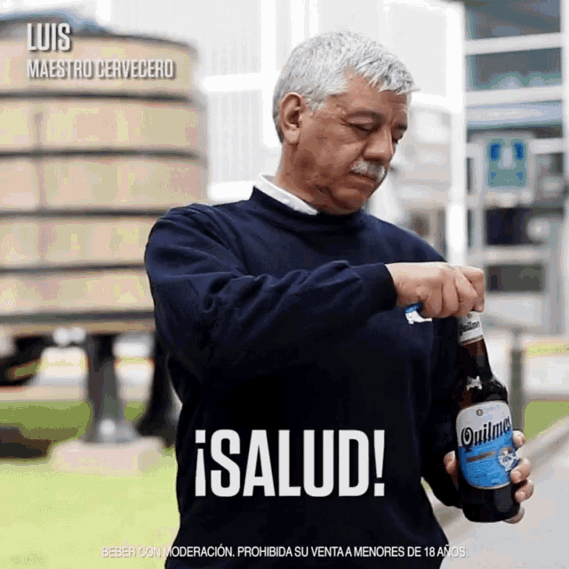 a man is holding a bottle of quilmes beer and says salud