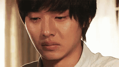 a close up of a young man crying with tears running down his face .