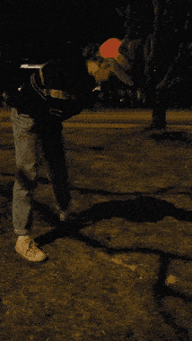 a man wearing a red hat is standing in the dark holding a hose