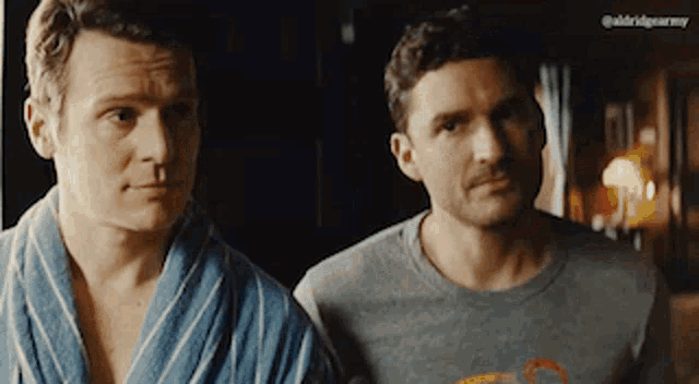 two men are standing next to each other and one is wearing a striped robe .