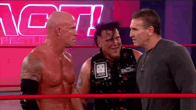 three men are standing in a wrestling ring and one of them has the word tcu on his vest .