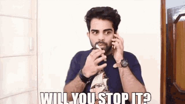 a man with a beard is talking on a cell phone and asking if he should stop it .