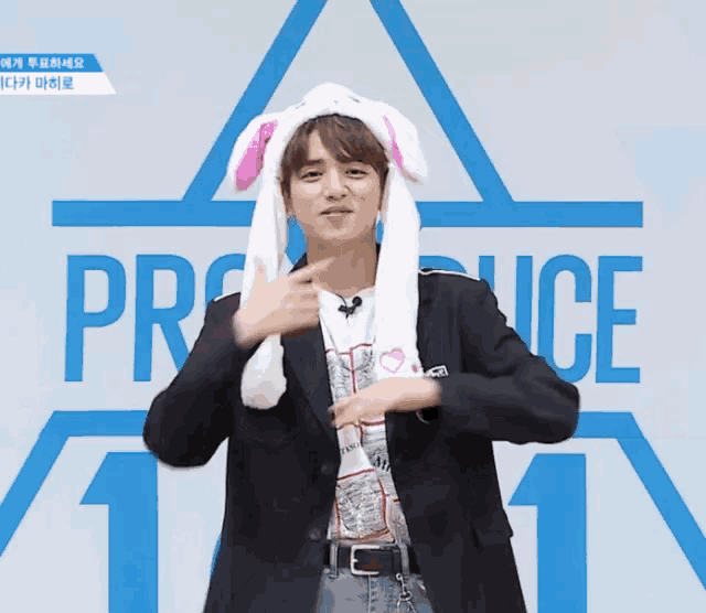 a man wearing bunny ears stands in front of a blue sign that says produce