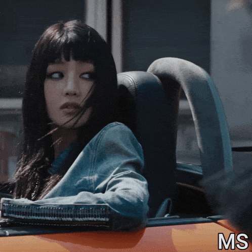 a woman is sitting in the back seat of an orange car with the letters ms below her