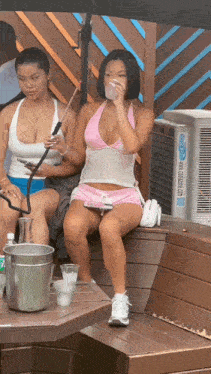 a woman in a pink top and shorts sits on a bench next to an air conditioner that says ' cooler air '