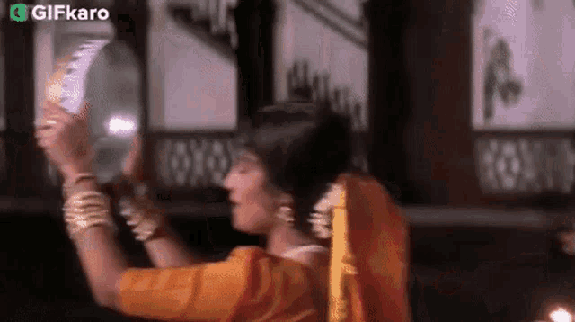 a woman in a sari is holding a fan in her hands and dancing .