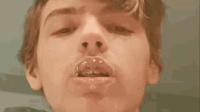 a close up of a young boy blowing a bubble in his mouth .