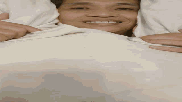a man laying under a white blanket with his eyes closed
