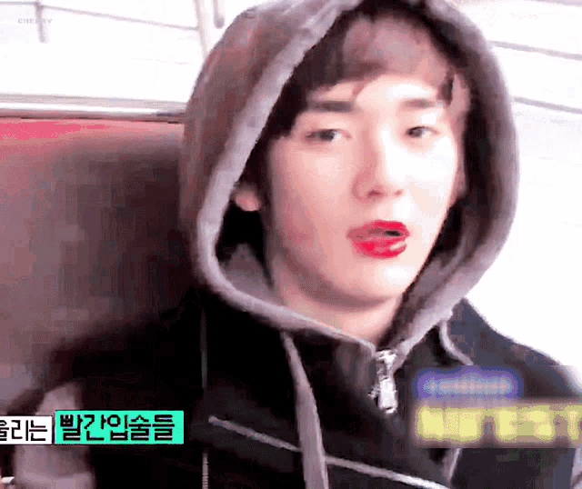 a young man wearing a hoodie and red lipstick