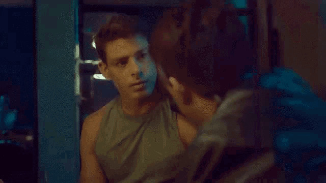 two men are sitting at a table talking to each other in a dark room .