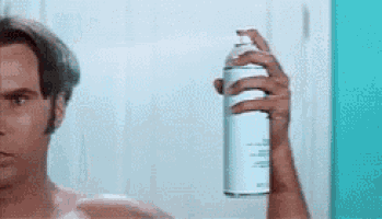 a man without a shirt is holding a spray can in front of a mirror .