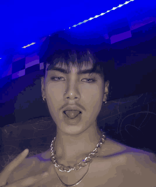 a young man wearing a chain around his neck is making a funny face