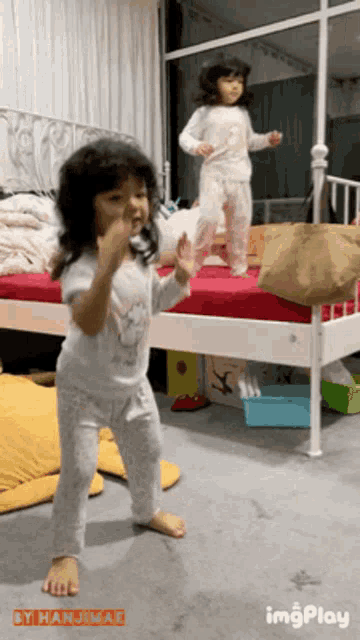 two little girls are jumping on a bed in a room with the words imgplay on the bottom