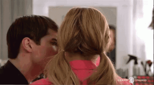 a man is kissing the back of a woman 's head in a room .