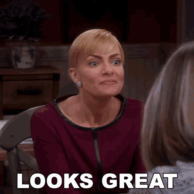 a woman sitting at a table with the words " looks great " behind her