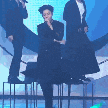 a man is singing into a microphone while standing on a stool