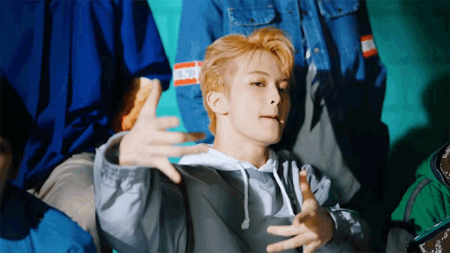 a man in a gray hoodie with a name tag that says ' nct dream '