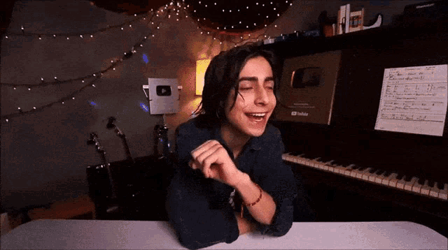 a young man sitting at a piano with his eyes closed and a youtube logo on the wall behind him
