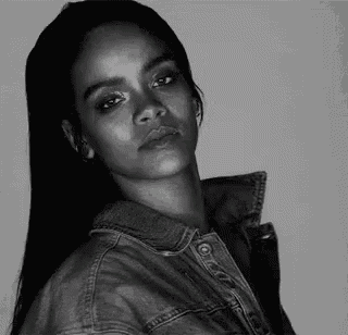 a black and white photo of a woman in a denim jacket looking at the camera .