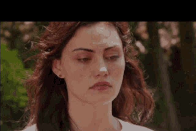 a close up of a woman 's face with a white shirt on