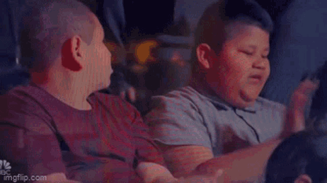 a man and a boy are sitting next to each other and the boy is saying yeeesssss !