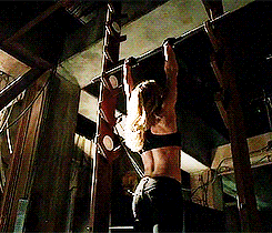 a woman is doing pull ups on a bar in a dark room