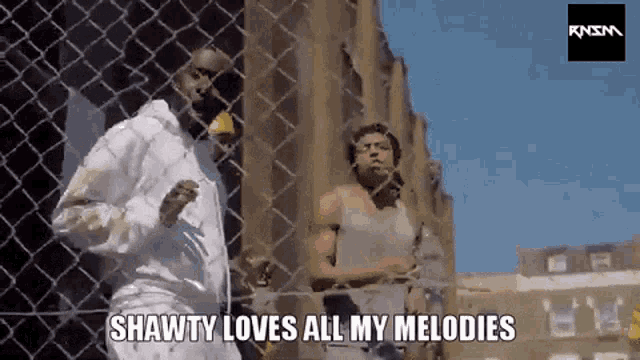 two men are standing behind a chain link fence and shawty loves all my melodies