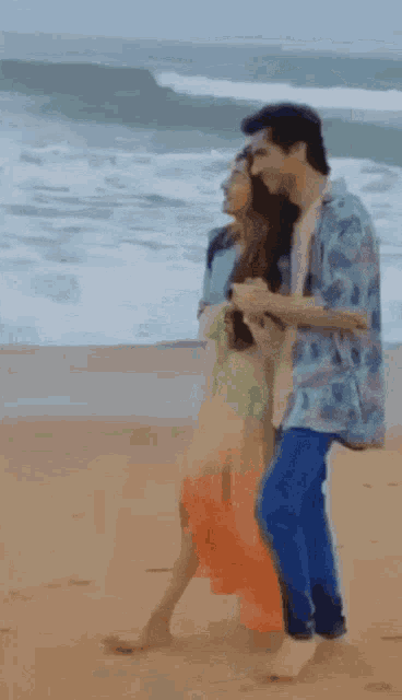 a man and a woman are walking on the beach
