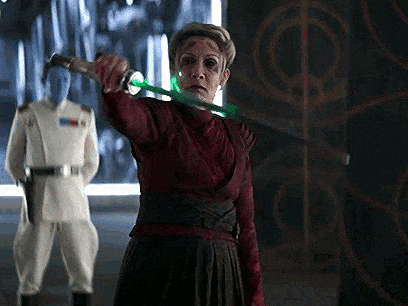 a woman is holding a green light saber in her hand .