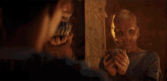 a man with a mask on his face looks at himself in the mirror