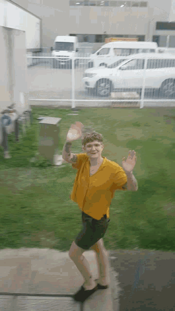 a man in a yellow shirt and black shorts is dancing