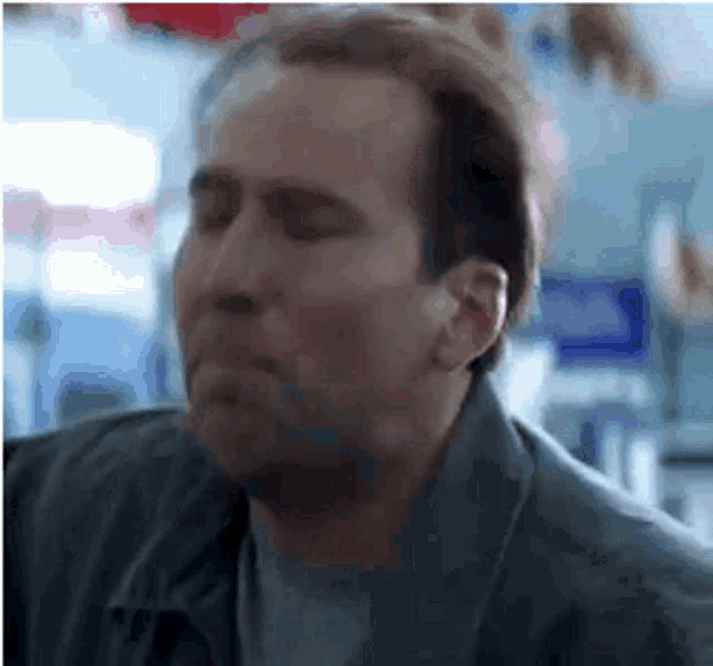 a man with his eyes closed is wearing a leather jacket and a gray shirt .
