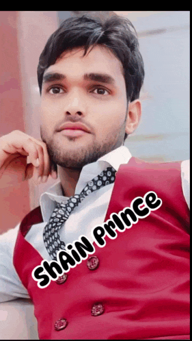 a man wearing a red vest and tie with the name shah prince on the bottom right