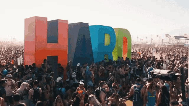 a large crowd of people are gathered in front of a large sign that says hard