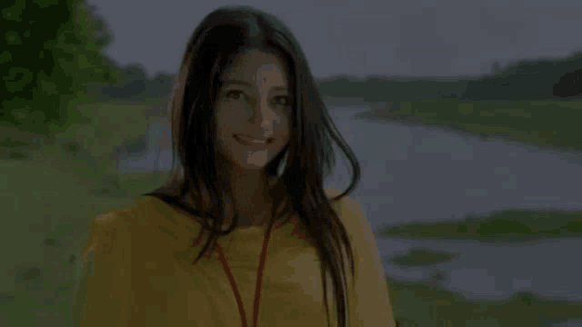 a woman wearing a yellow shirt with a red lanyard around her neck smiles