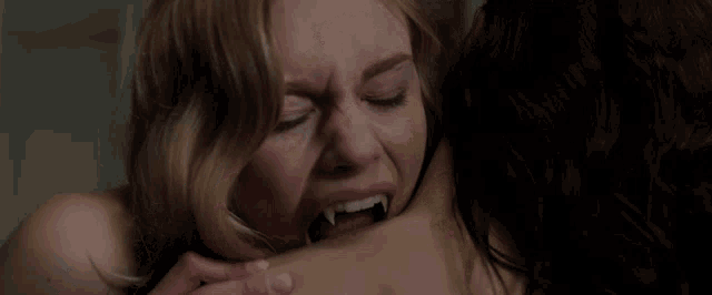 a woman with vampire teeth is crying while another woman holds her