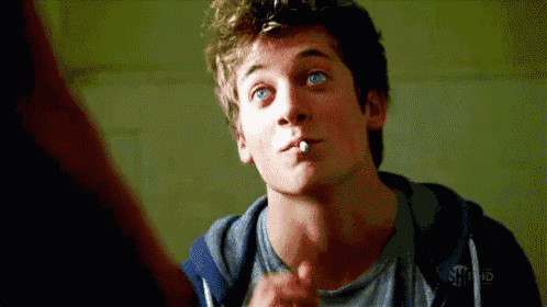a young man is smoking a cigarette and pointing at something .