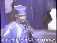 a man in a graduation cap and gown is holding a microphone and talking into it .